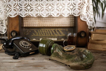 Vintage gas mask and old-fashioned rotary dial phone, relics of the past, evoking sense history and...