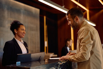 Hotel guest signing paperwork at reception desk.
