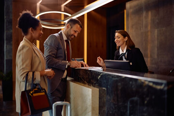 Happy business couple checking in at hotel.