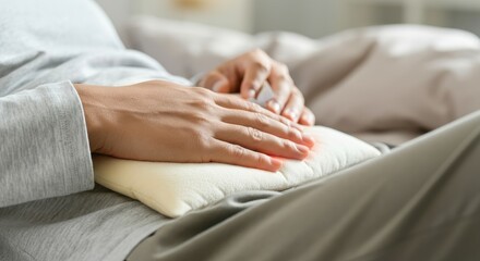 Person using heating pad on stomach for pain relief, close-up