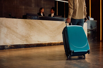 Close up of man with travel bag in hotel hallway.