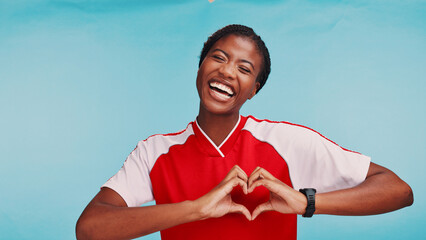 Portrait, heart hands and woman in studio, soccer player and symbol for love on blue background. African person, model and athlete with gesture, sports and support with female empowerment or kindness © Clayton Daniels/peopleimages.com
