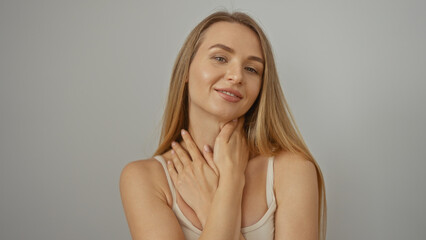 Fototapeta premium Woman posing against a white background exhibits confidence and elegance, showcasing her attractive blonde features and charming expression.