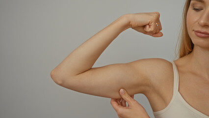 Fototapeta premium Woman flexing arm muscle showing strength isolated on white background symbolizing health fitness selfcare empowerment and motivation.