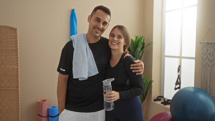 Man and woman smiling together indoors at gym showing love and companionship in a sports center setting, highlighting their relationship and fitness routine.