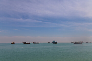 Obraz premium Fishing vessels rest in the calm waters of Bushehr, embraced by the endless sky and serene sea.