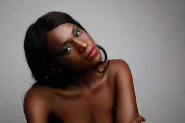 Portrait of beautiful, young African American woman with glow skin posing over light background.