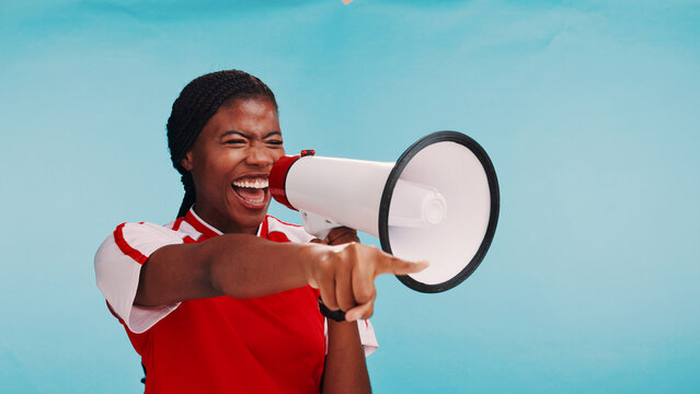 Woman, loudspeaker and happy in studio with sports, pointing and choice for football team recruitment. African person, bullhorn and excited for talent, competition and call to action for soccer - Powered by Adobe