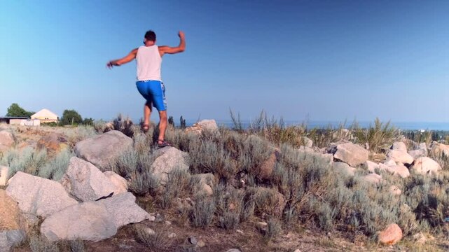 A crossfitter leaps from stone to stone, building strength, endurance, and coordination. The rugged terrain and rocks enhance conditioning, boosting readiness for intense training.
