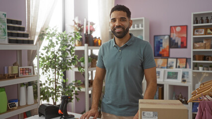 Fototapeta premium Handsome young man smiling in a well-decorated home decor store with shelves of merchandise and a green plant in the background