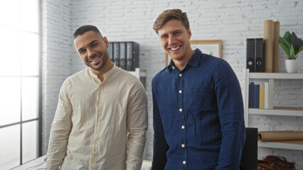 Handsome men working as business partners smiling confidently in a modern office interior, showcasing teamwork and professional collaboration goals