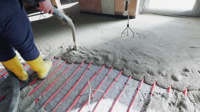 Construction worker pouring self-leveling screed over underfloor heating