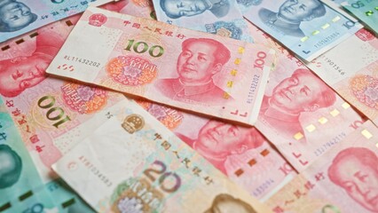 Chinese yuan banknotes of various denominations scattered on a flat surface showcasing the currency...