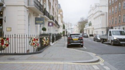 Blurred street scene captures a wintery london with festive decorations, parked cars, and traditional architecture, conveying a serene urban atmosphere.