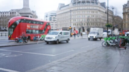 Blurred view of london's trafalgar square featuring iconic red bus in winter, capturing urban...