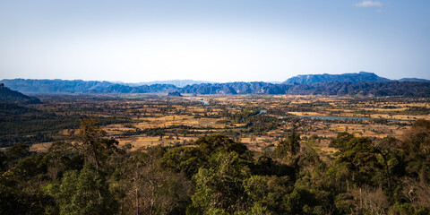 A panoramic view of the landscape in Laos, showcasing the vast valleys, mountains, and forests.