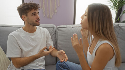 Man and woman talking on a couch in a cozy apartment living room, illustrating a warm and candid interaction in a modern home setting with natural decor elements.