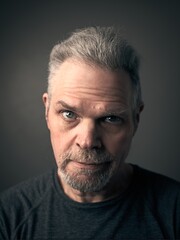 Obraz premium Dark Portrait of mature caucasian man looks straight at camera. Vertical image with soft focus. 