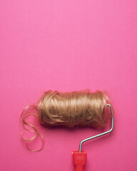 Surreal creative concept of paint roller with blonde hair on vibrant pink background. Minimalism,...