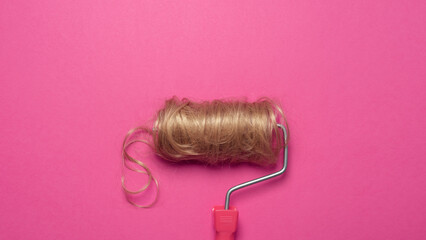 Cascading blonde hair on paint roller against bold pink merges beauty, transformation, and surreal...