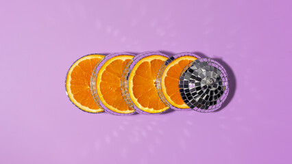 Creative sliced disco ball revealing fresh juicy orange inside on vivid purple background, evoking cheerful mood and party vibes.