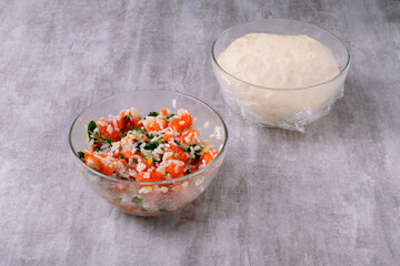 Filling of raw trout fillet, rice with fried onions and yeast dough on a gray background. Ingredients for making baked goods with fish filling on a gray background. Step by step