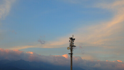Cell Site Digital Cellular Telecommunication Tower Network Antenna on sunset orange blue sky...