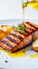 Grilled salmon with dill and fried potatoes drizzled with olive oil on a white plate