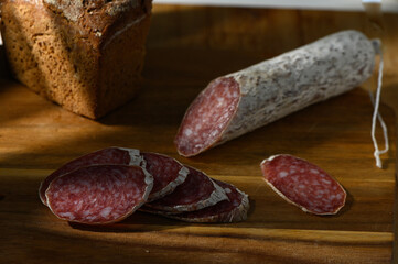 Savory slices of cured salami beside freshly baked bread on a rustic wooden board