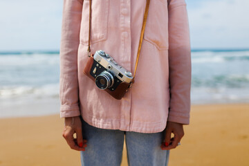 Close-up of a film camera. young girl in a stylish pink shirt and jeans. World Traveler, Travel Blogger and Content Creator