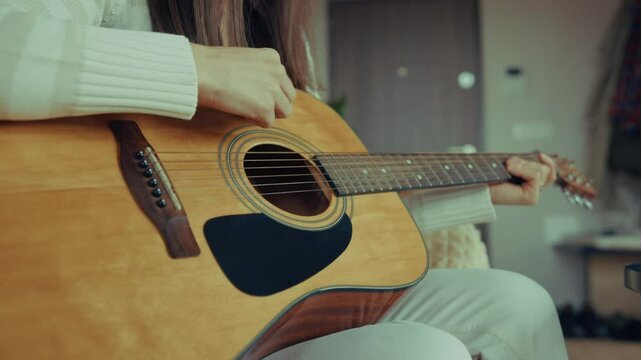 Woman musician playing acoustic guitar at home