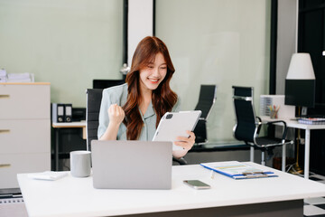 Asian business woman are delighted and happy with the work they do on their tablet, laptop and...