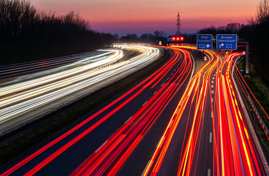 Dortmund-Unna Autobahn (A44 and A1) interchange in the Ruhr area (Germany) with heavy traffic on a winter evening after sunset. Numerous vehicles leave white, yellow and red light trails on the road. 