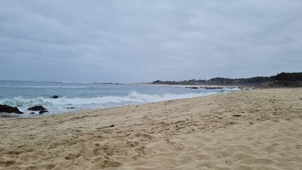 Breathtaking view of Chile’s Pacific coast, featuring rugged rocks, golden sandy beach, and waves under a bright sky. Perfect for travel, nature, and coastal landscapes.
