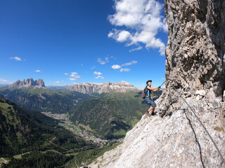 High on a rocky precipice, a figure gazes across a sprawling valley embraced by towering mountains, capturing the exhilarating freedom of exploration and the breathtaking natural panorama