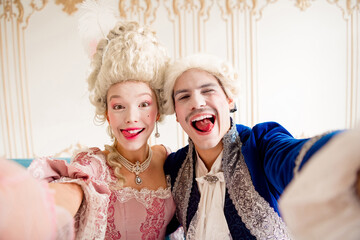Playful couple dressed in elegant baroque costumes taking a cheerful selfie indoors