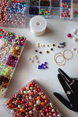 Hand figurine, colorful friendship bracelets, necklaces, various beads and DIY supplies on the table. Making jewelry at home. Flat lay.