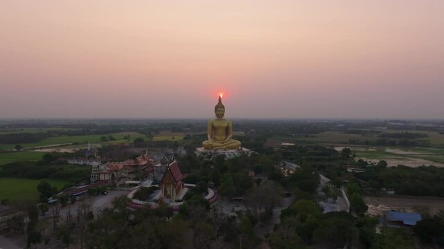 Majestic Buddha figure glowing in sunlight at Wat Muang, Thailand. Aerial drone video