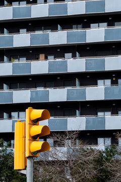 Urban residential building with balconies and a prominent yellow traffic light.
