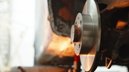 Skilled automotive technician performing brake disc replacement, wearing protective gear while maintaining vehicle safety standards in professional repair facility