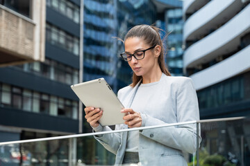 Portrait of a successful business woman using digital tablet in front of modern business building. Businessperson office worker design professional occupation, innovative work outside of workspace.
