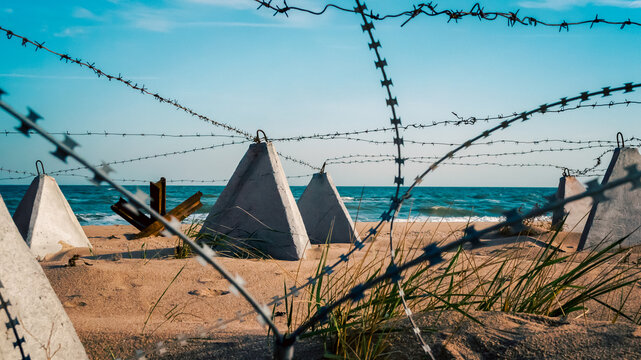 barbed wire and concrete military fence on the beach near the sea in Crimea