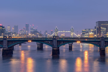 Obraz premium Illuminated buildings of the London United Kingdom city skyline along the Thames River. Photo contains the iconic London Tower Bridge.