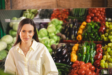 Young woman girl portrait buyer client consumer stands in shop store supermarket choosing food buying puts it. Woman choose fruits and vegetables on farmer market.