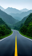 Naklejka premium Winding asphalt road through lush green mountains under a misty sky
