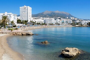 A coastal scene shows buildings and a mountain range