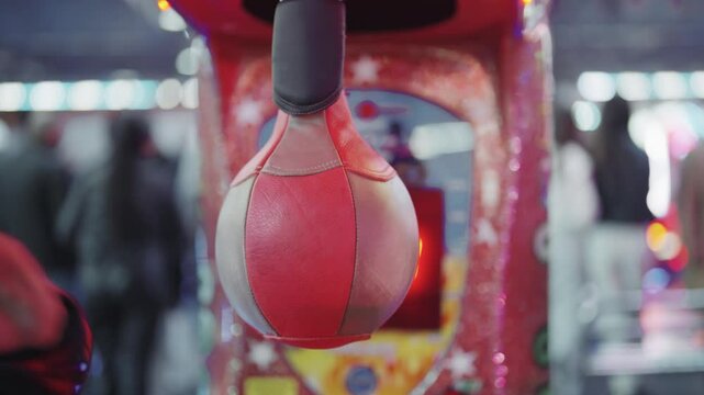 Man punching bag arcade game machine in a lively fun park, slow motion