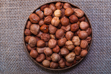 Bowl of whole hazelnuts on burlap background
