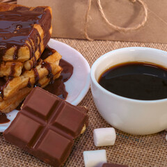 Coffee with chocolate-covered waffles and marshmallows on burlap