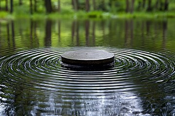 A circular stone platform creates ripples in a reflective body of water